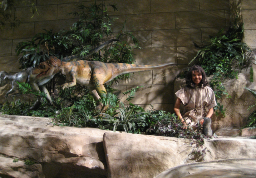 Photo taken at the Creation Museum showing dinosaurs and a child together.