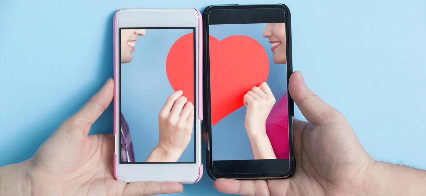 Photo of two cell phones each with half of the same heart on it, used for a StarTalk All-Stars episode about whether technology is changing love. Credit: RyanKing999/iStock.