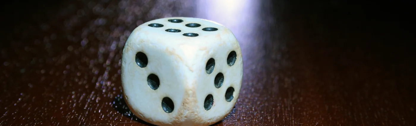 Storyblocks Photo of a Single White and Black Dice on a Wooden Table.