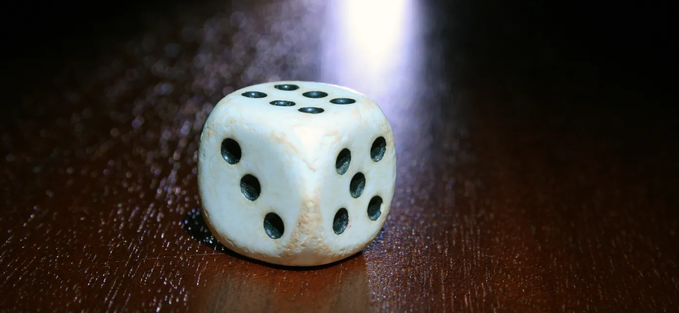 Storyblocks Photo of a Single White and Black Dice on a Wooden Table.