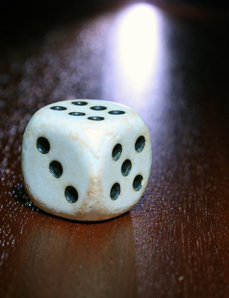 Storyblocks Photo of a Single White and Black Dice on a Wooden Table.