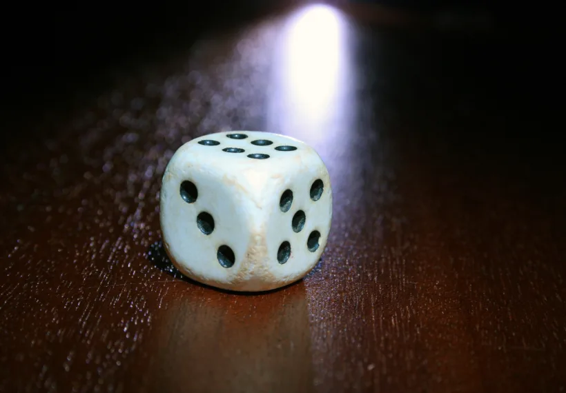 Storyblocks Photo of a Single White and Black Dice on a Wooden Table.