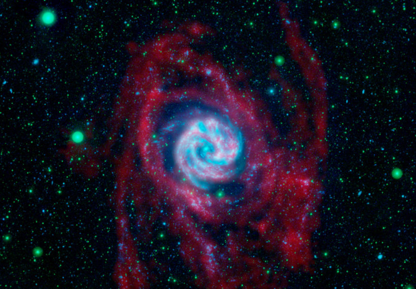 The outlying regions around the Southern Pinwheel galaxy, or M83, are highlighted in this composite image from NASA's Galaxy Evolution Explorer and the National Science Foundation's Very Large Array in New Mexico. The blue and pink pinwheel in the center is the galaxy's main stellar disk, while the flapping, ribbon-like structures are its extended arms.