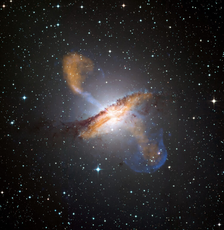 This image of Centaurus A shows a spectacular new view of a supermassive black hole's power. Jets and lobes powered by the central black hole in this nearby galaxy are shown by submillimeter data (colored orange) from the Atacama Pathfinder Experiment (APEX) telescope in Chile and X-ray data (colored blue) from the Chandra X-ray Observatory. Visible light data from the Wide Field Imager on the Max-Planck/ESO 2.2 m telescope, also located in Chile, shows the dust lane in the galaxy and background stars. The X-ray jet in the upper left extends for about 13,000 light years away from the black hole. The APEX data shows that material in the jet is travelling at about half the speed of light.