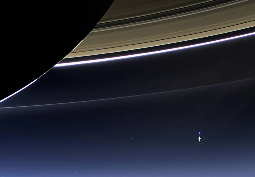 NASA's Cassini spacecraft photographs Earth from Saturn, 900 million miles away. Earth is pointed out by an arrow.
