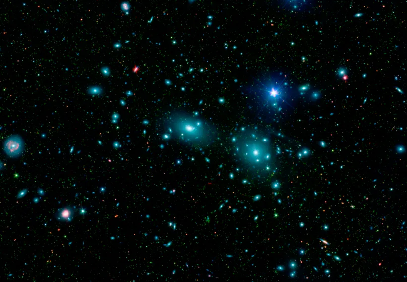 This false-color mosaic of the central region of the Coma cluster combines infrared and visible-light images to reveal thousands of faint objects (green). Follow-up observations showed that many of these objects, which appear here as faint green smudges, are dwarf galaxies belonging to the cluster. Two large elliptical galaxies, NGC 4889 and NGC 4874, dominate the cluster's center. The mosaic combines visible-light data from the Sloan Digital Sky Survey (color coded blue) with long- and short-wavelength infrared views (red and green, respectively) from NASA's Spitzer Space Telescop