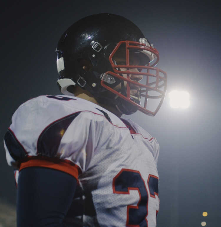 Portrait Of A Confident Football Player Standing On The Field At Night
