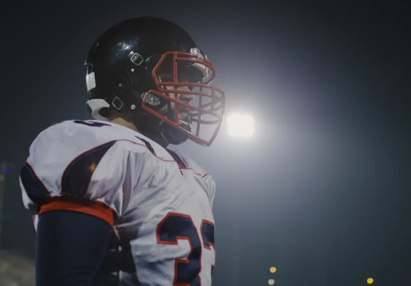 Portrait Of A Confident Football Player Standing On The Field At Night