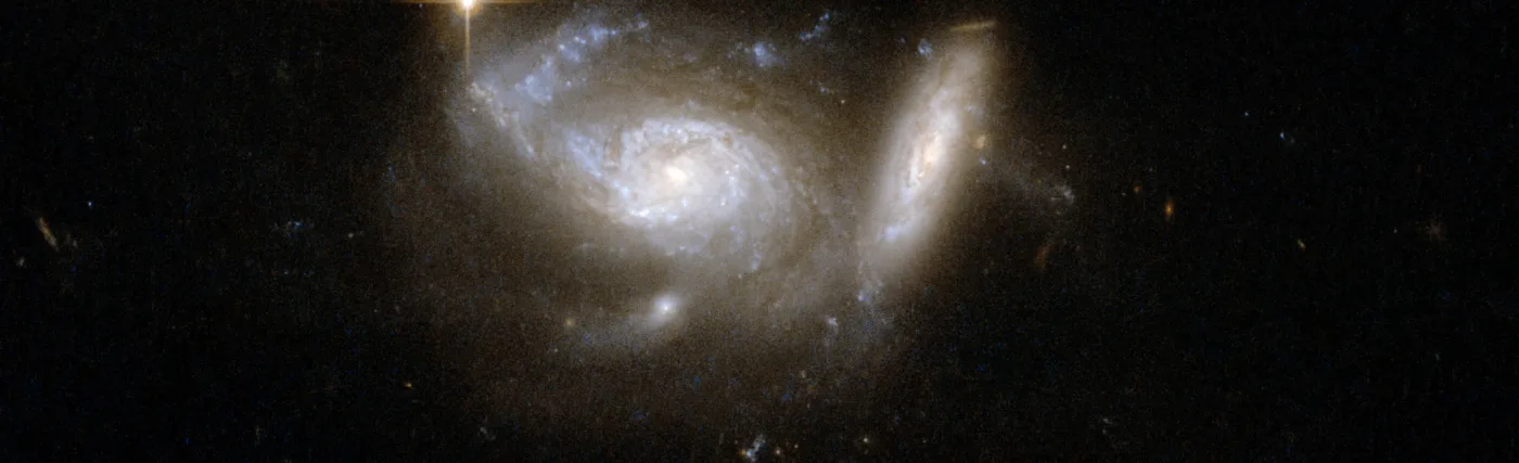 ESO 550-2 shows a pair of spiral galaxies, the larger nearly face-on and accompanied by a smaller, highly tilted partner. Tidal interaction from the smaller companion has clearly deformed one arm of the larger galaxy. Strong star formation continues both in the deformed arm and in a ring structure around the galaxy's core. The pair is surrounded by the glow of faintly shining stars and interstellar matter that has been smeared through space by the gravitational effects of the collision and the pull of a third nearby galaxy.