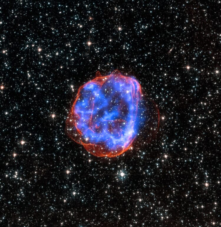 X-ray & Optical Images of SNR E0519-69.0 - When a massive star exploded in the Large Magellanic Cloud, a satellite galaxy to the Milky Way, it left behind an expanding shell of debris called SNR 0519-69.0. Here, multimillion degree gas is seen in X-rays from Chandra (blue). The outer edge of the explosion (red) and stars in the field of view are seen in visible light from Hubble.