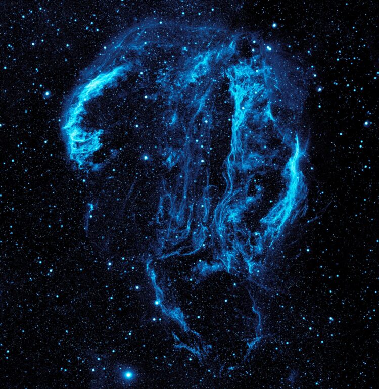 Wispy tendrils of hot dust and gas glow brightly in this ultraviolet image of the Cygnus Loop Nebula, taken by NASA’s Galaxy Evolution Explorer.