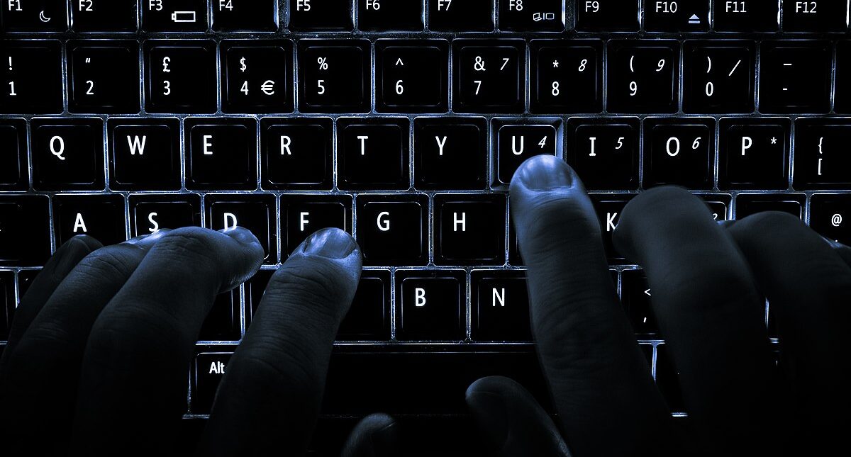 A backlit laptop computer keyboard being used.