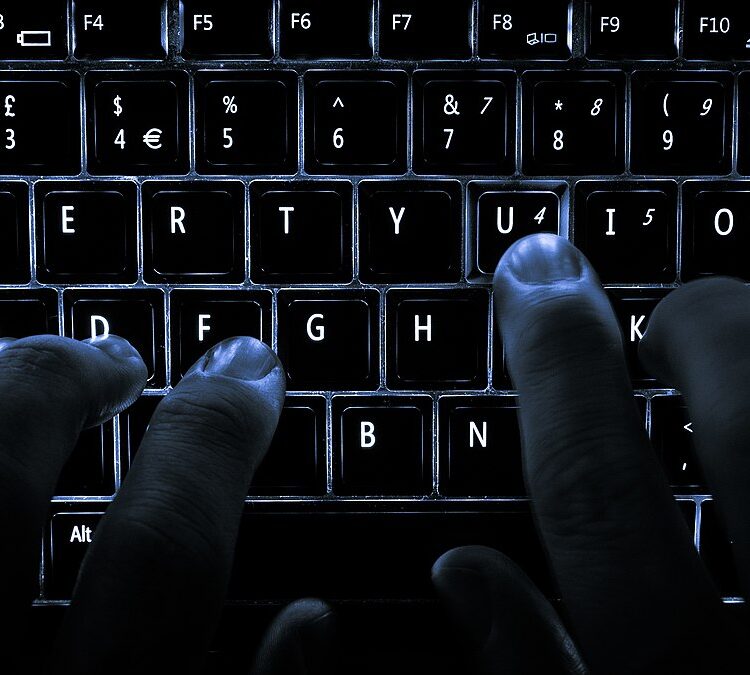 A backlit laptop computer keyboard being used.