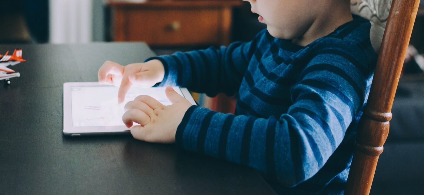 A child playing with an iPad while seated at a table