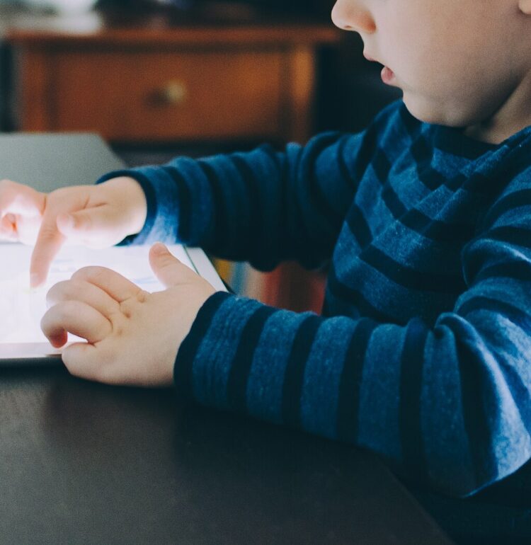 A child playing with an iPad while seated at a table
