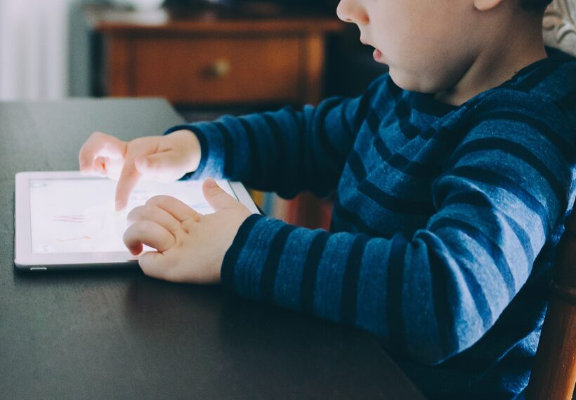 A child playing with an iPad while seated at a table