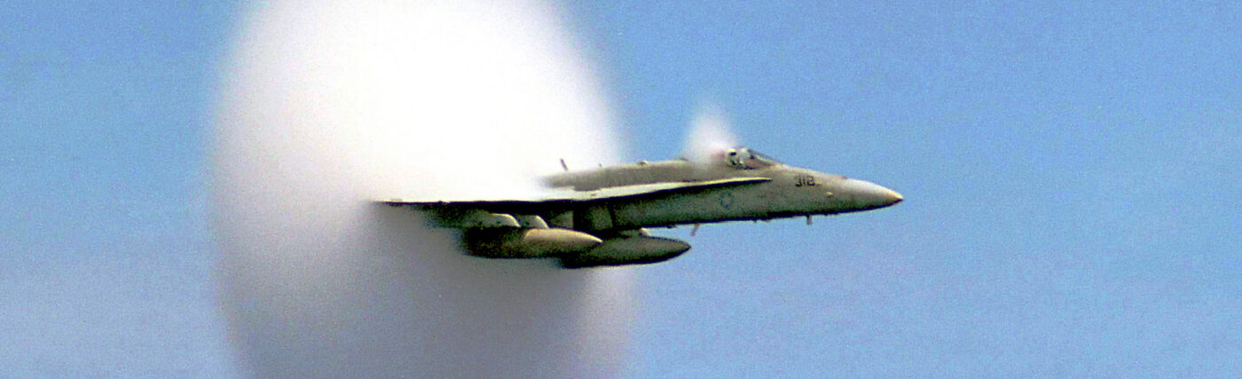 A cloud forms as this F/A-18 Hornet aircraft speeds up to supersonic speed.