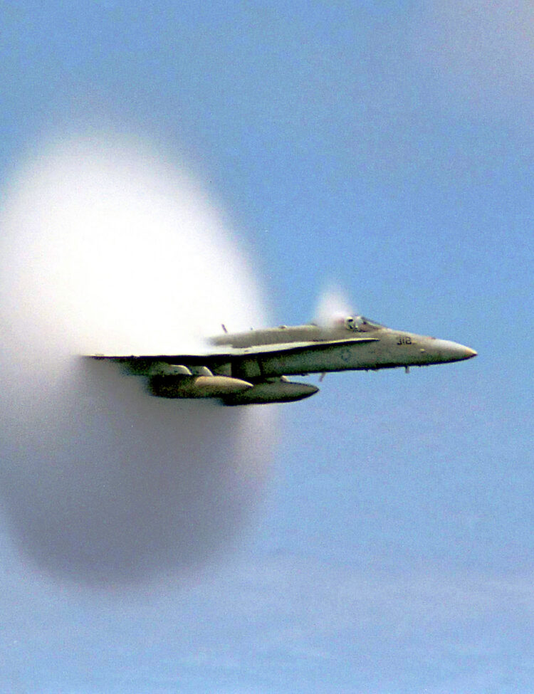 A cloud forms as this F/A-18 Hornet aircraft speeds up to supersonic speed.