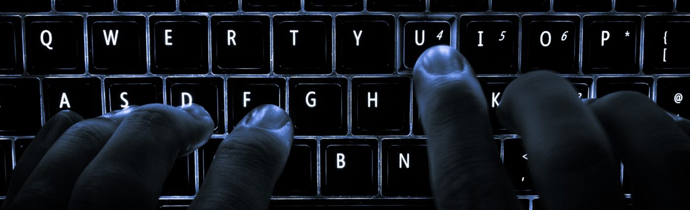 A backlit laptop computer keyboard. Most fingers are on the "home" keys for touch-typing; the 'U' key is being pressed.