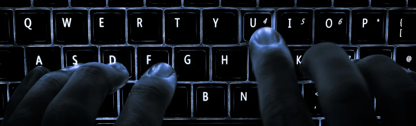 A backlit laptop computer keyboard. Most fingers are on the "home" keys for touch-typing; the 'U' key is being pressed.