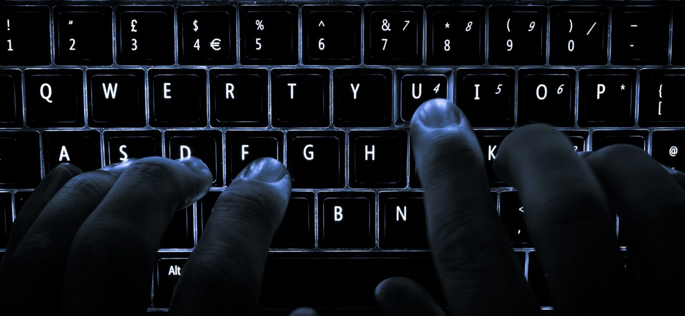 A backlit laptop computer keyboard. Most fingers are on the "home" keys for touch-typing; the 'U' key is being pressed.