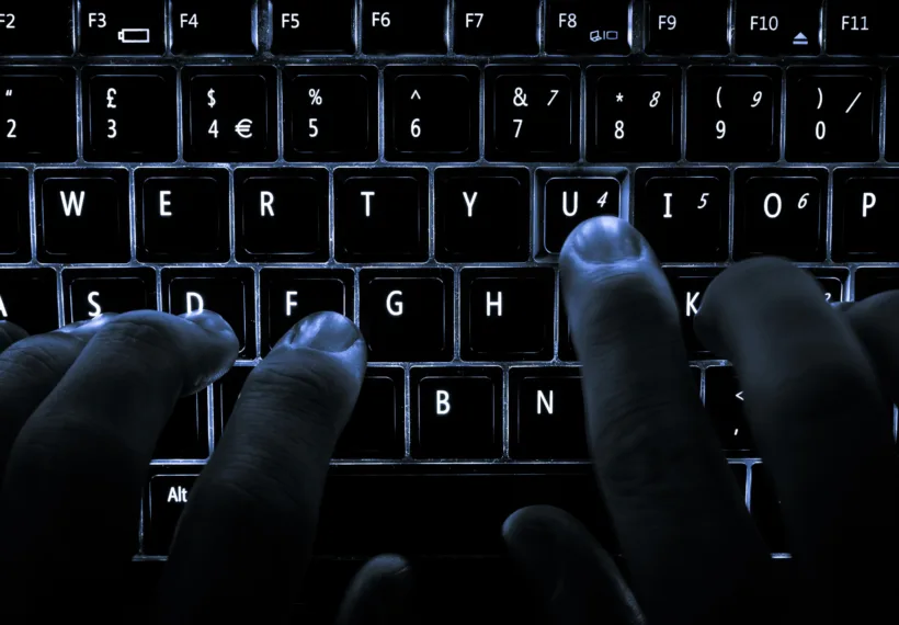 A backlit laptop computer keyboard. Most fingers are on the "home" keys for touch-typing; the 'U' key is being pressed.